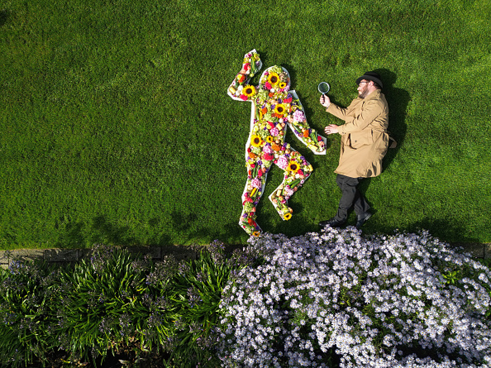 Мъж позира в ролята на детектив до флорална инсталация в очертано с тебешир "местопрестъпление". Снимка: Getty Images